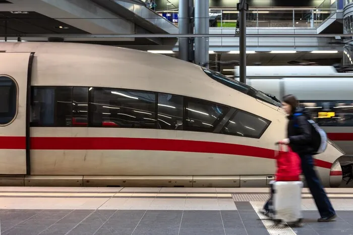 Un voyageur avec une valise longe un train sur un quai de gare