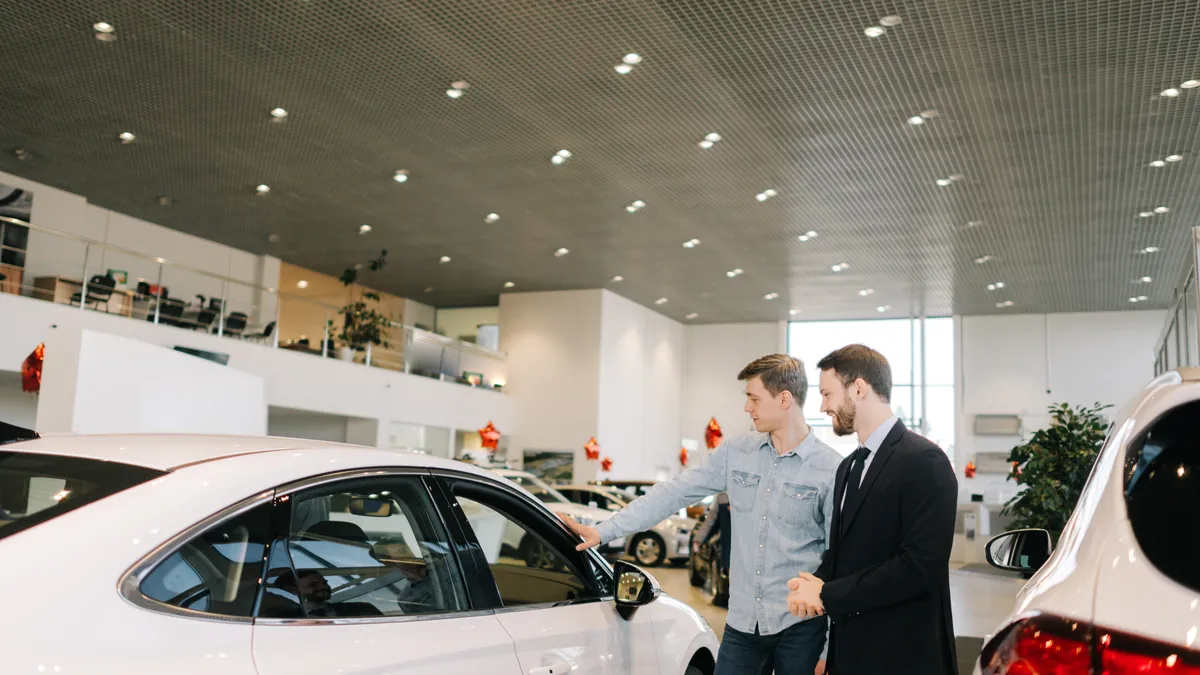 Um vendedor mostra um carro novo a um comprador num stand de automóveis