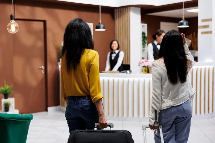 スーツケースを引いた2人の宿泊客がホテルのフロントへ向かう。