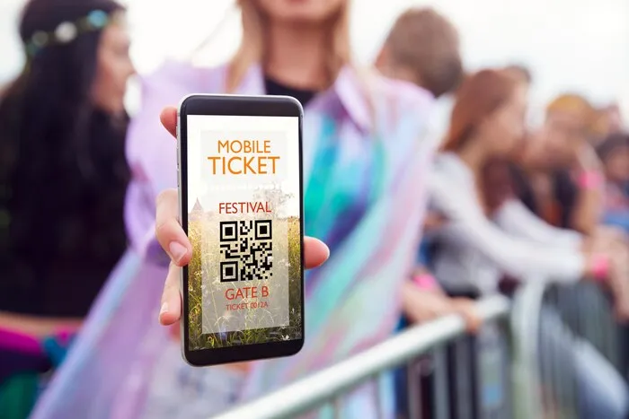 Une fan présente un billet sur mobile à l'entrée d'un festival. Les billets de Bangkok sont uniquement sur mobile et chacun porte le nom de son titulaire.