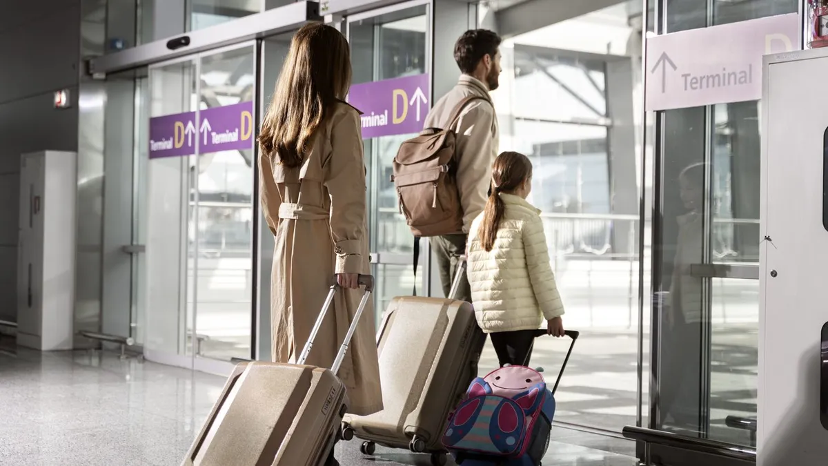 A family walks with suitcases through an airport terminal.