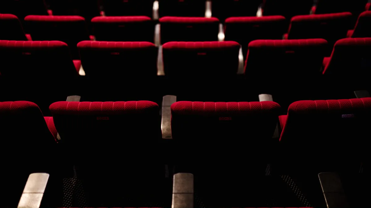 Rows of empty red velvet seats in a darkened theatre