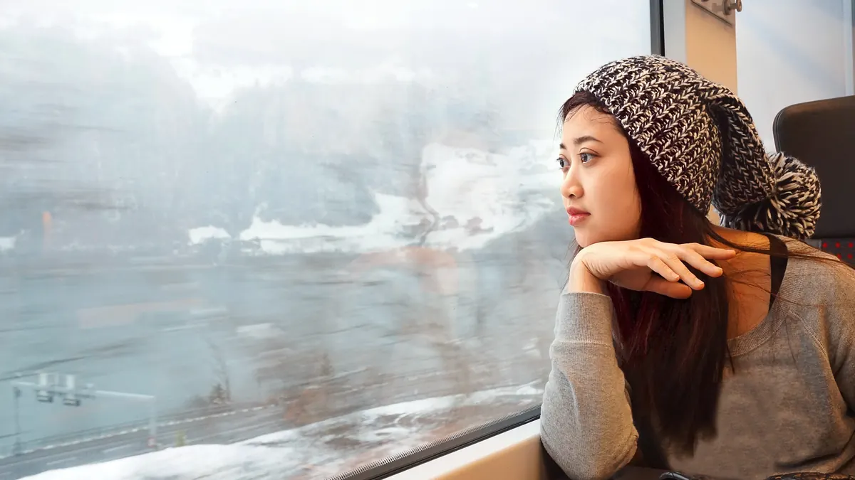A traveller looks out of a train window at a snowy landscape