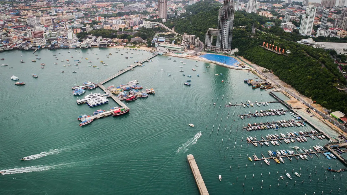 A baía de Pattaya vista do ar, com cais e barcos em frente à cidade.