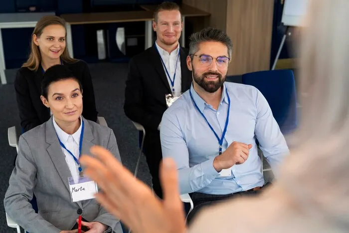 Delegierte mit Namensschildern sitzen bei einer Business-Veranstaltung zusammen.