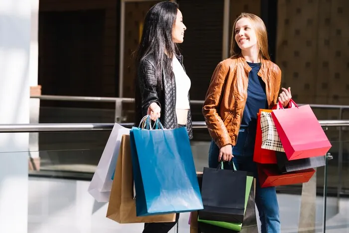Des clients chargés de sacs traversent un grand magasin.