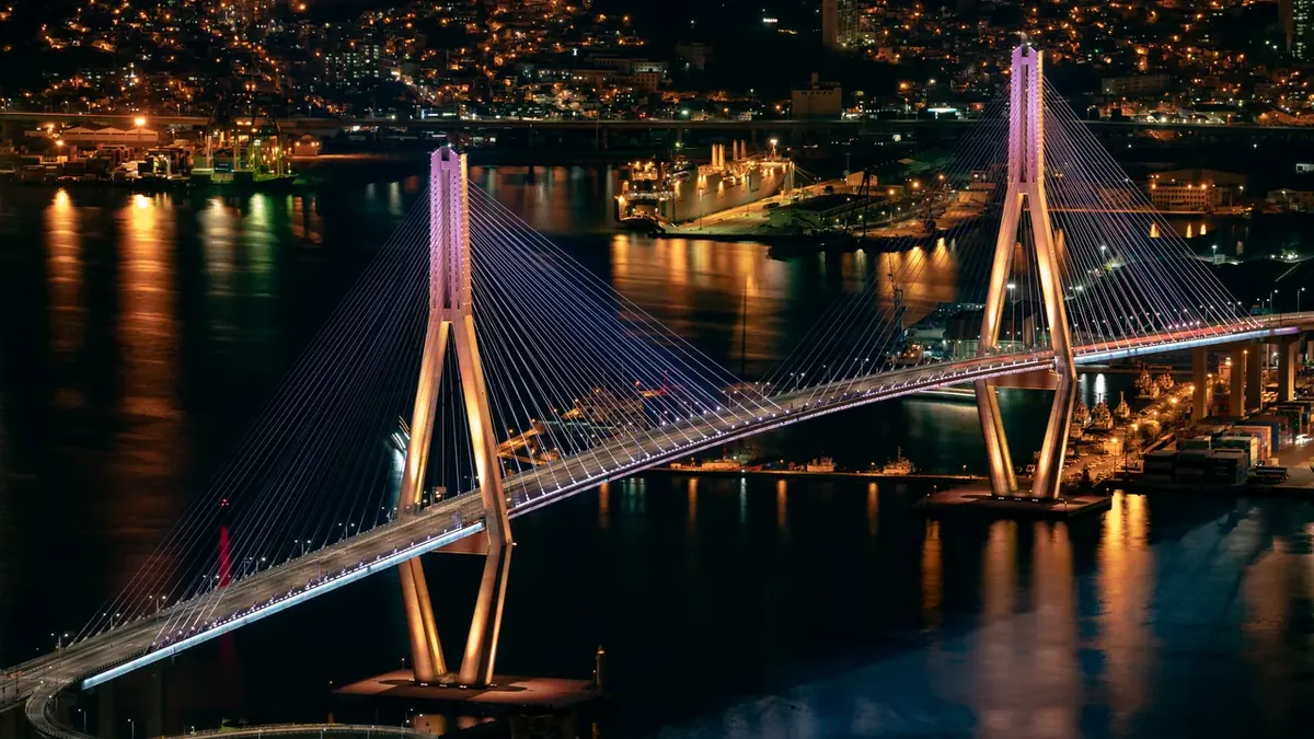 El puente del puerto de Busan iluminado de noche sobre el puerto