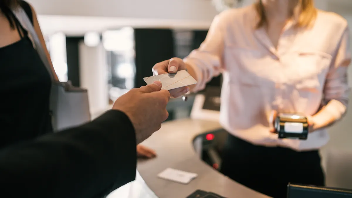 A guest hands a card to a receptionist at a hotel front desk