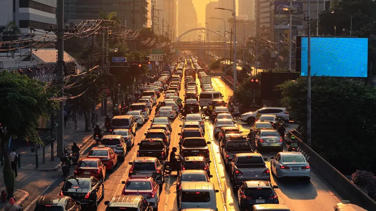 Trânsito do fim do dia parado numa avenida ao pôr do sol.