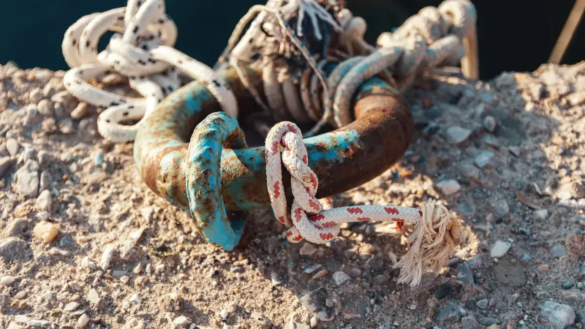 Cabos atados a una argolla de amarre oxidada en un muelle de hormigón