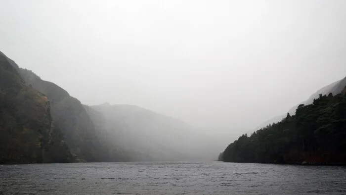 雨水和低云在暗色山丘间的湖面上合拢