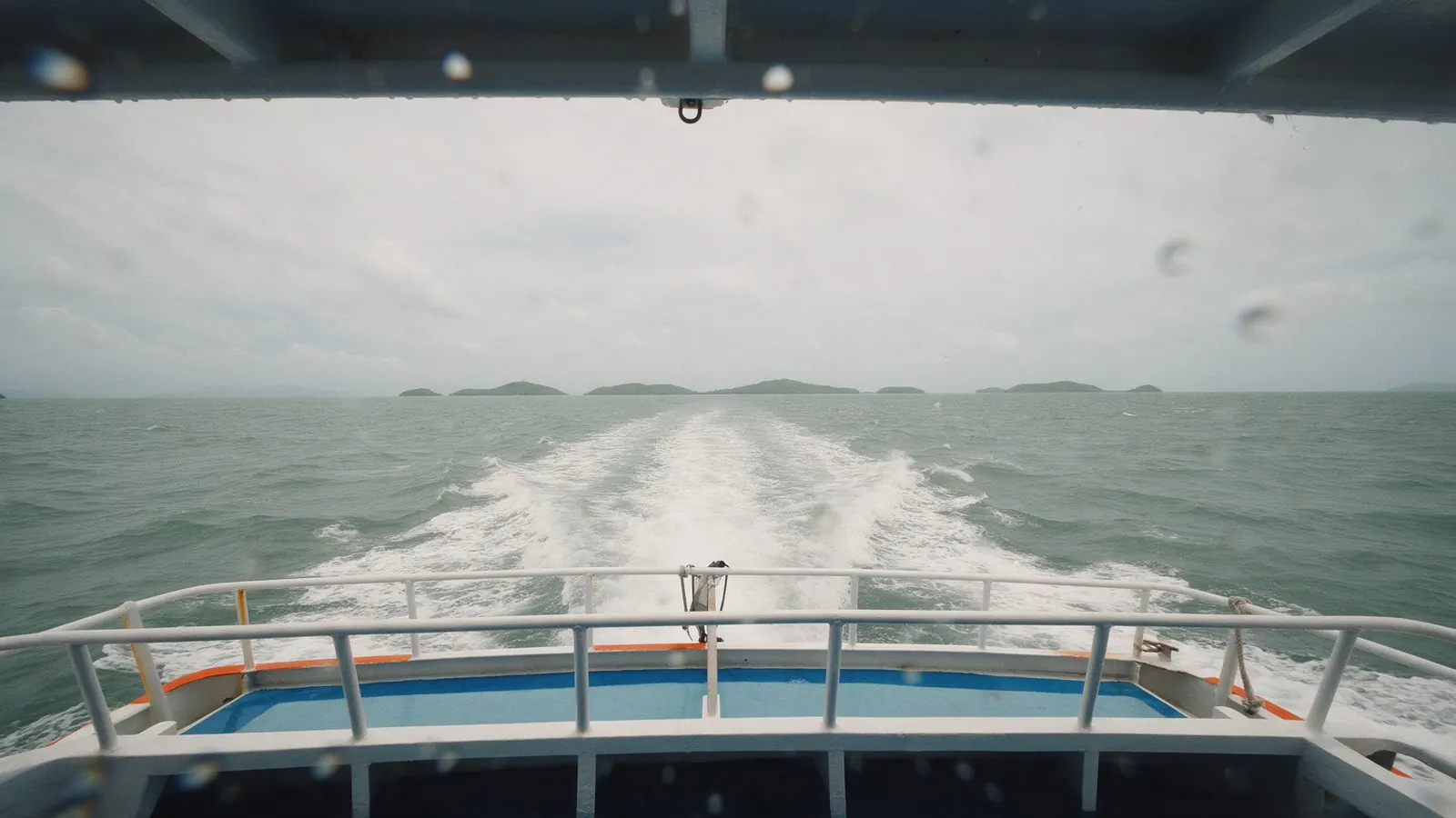Das Kielwasser einer schnellen Fähre auf dem Weg zu flachen Inseln an einem grauen Tag: Ein Inseltag beginnt und endet im Hafen.