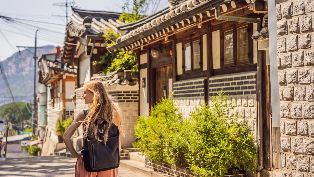 Une visiteuse longe une ruelle de hanok à Bukchon. De nombreux quartiers anciens de Séoul sont résidentiels : les groupes les parcourent donc discrètement.