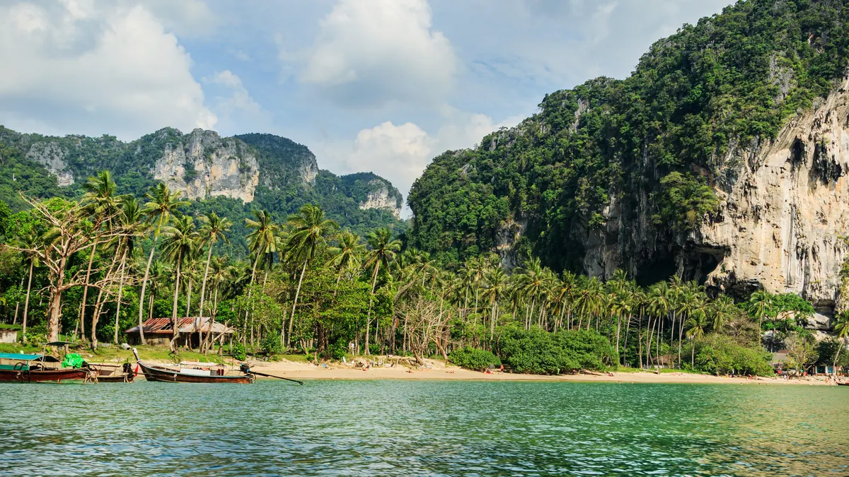 Bateaux longue-queue et falaises calcaires sur une plage de Krabi