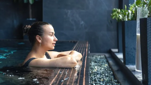 A guest resting at the edge of an indoor spa pool