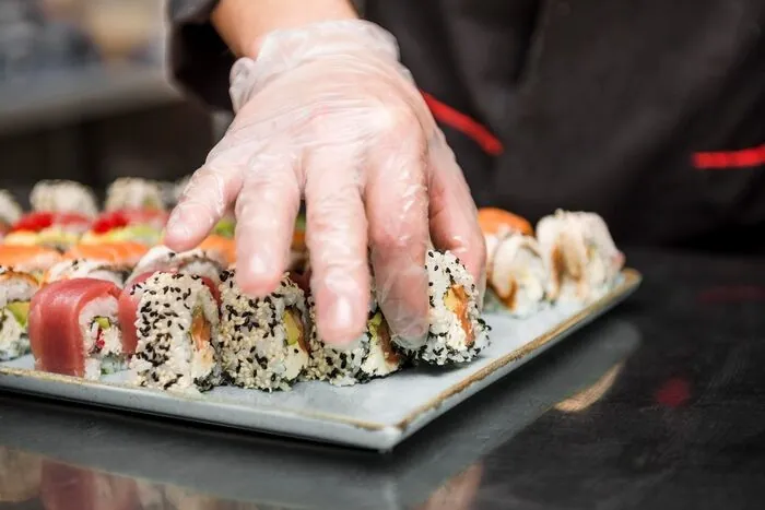 Um cozinheiro de luvas a arrumar sushi num tabuleiro: no autocarro, o sushi é preparado no piso inferior e sobe até aos comensais.