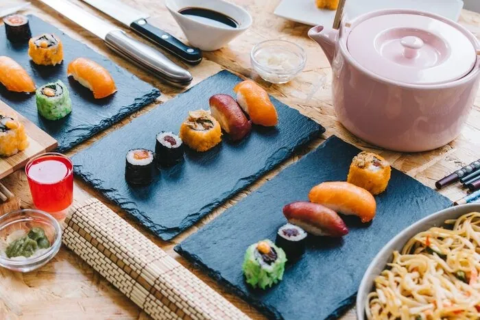 Sushi, um bule e pratos pequenos numa mesa: no autocarro as bebidas estão incluídas, e as necessidades alimentares são verificadas antes da reserva.