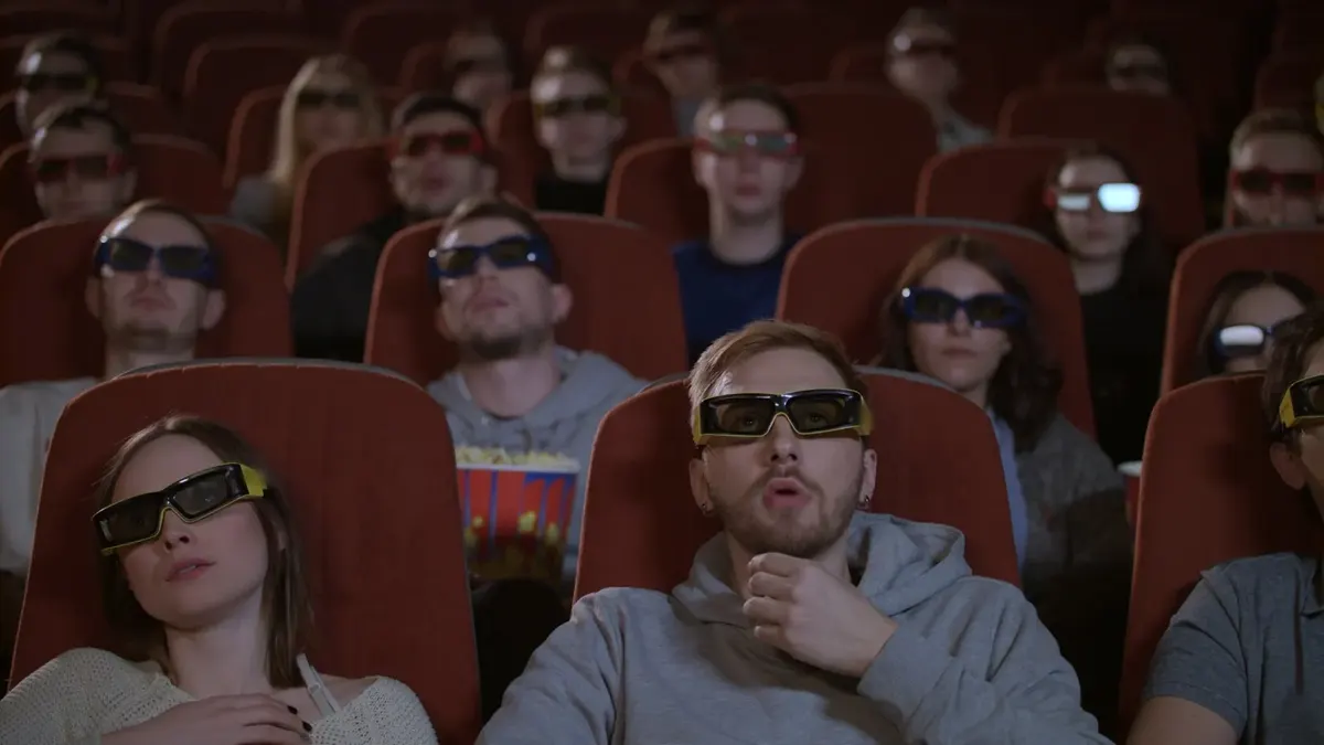 جمهور في قاعة سينما يشاهد فيلمًا بنظارات ثلاثية الأبعاد.