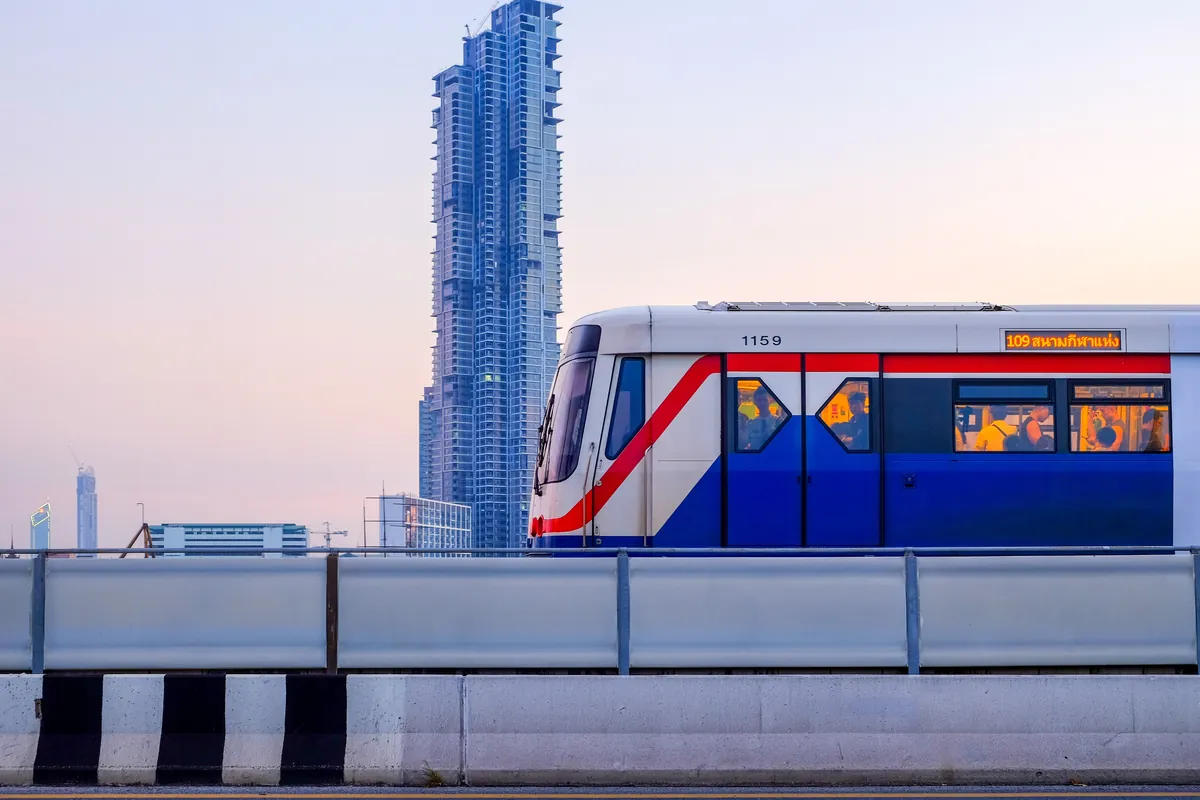قطار BTS Skytrain على مساره المرتفع في بانكوك وخلفه برج شاهق