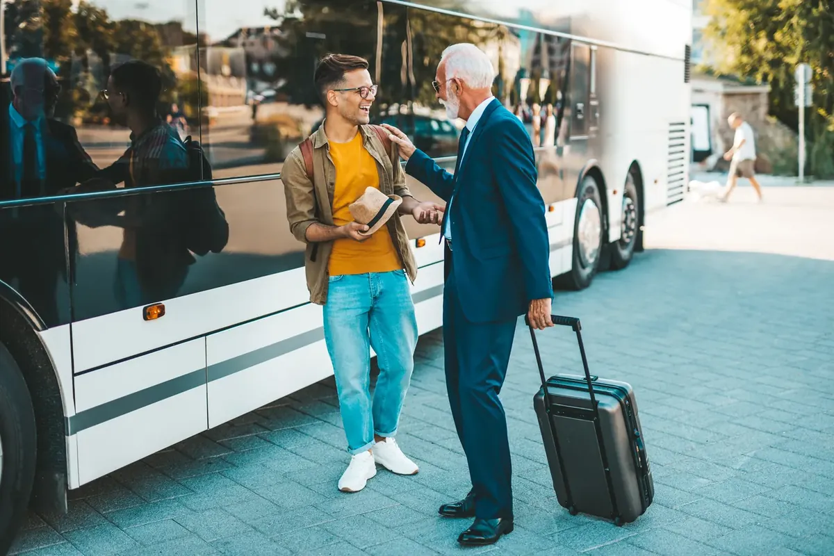 A coach driver taking a passenger's suitcase beside a coach