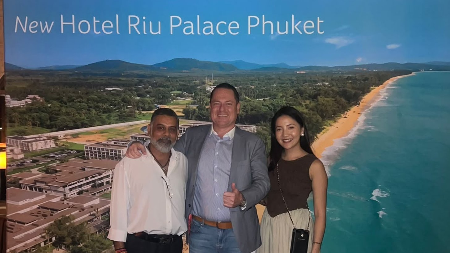 Riu Palace Phuketのディスプレイの前でRIU Hotels & Resortsチームと並ぶExpleraのディレクター
